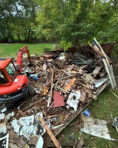 Mini excavator breaking down a collapsed outbuilding