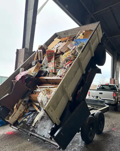 Dump trailer tipping a full load of household junk